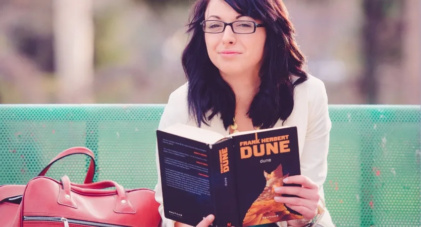 mulher lendo um livro em uma praça - bolsa transversal personalizada