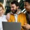 Três colegas de trabalho sorrindo em frente a um notebook durante processo de onboarding nas empresas.