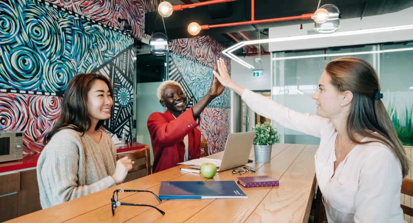 Equipe comemorando com high five em sala de reunião moderna durante onboarding nas empresas.