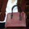 Bolsa estruturada elegante em tom vinho apoiada em sofá, representando estilo atemporal e sofisticação