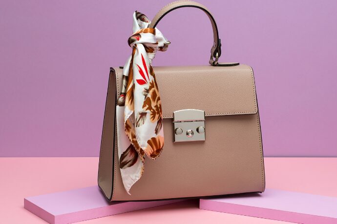 Bolsa estruturada sofisticada com lenço decorativo em fundo minimalista, representando estilo de vida elegante