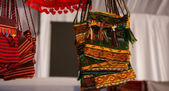 Bolsa de tecido artesanal com padronagem colorida em estilo country chic, pendurada em ambiente rústico e elegante.