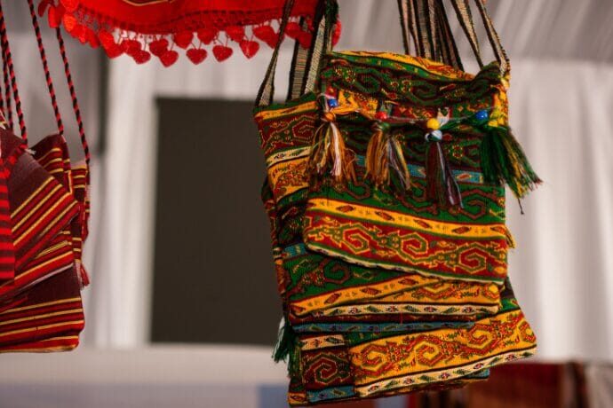 Bolsa de tecido artesanal com padronagem colorida em estilo country chic, pendurada em ambiente rústico e elegante.