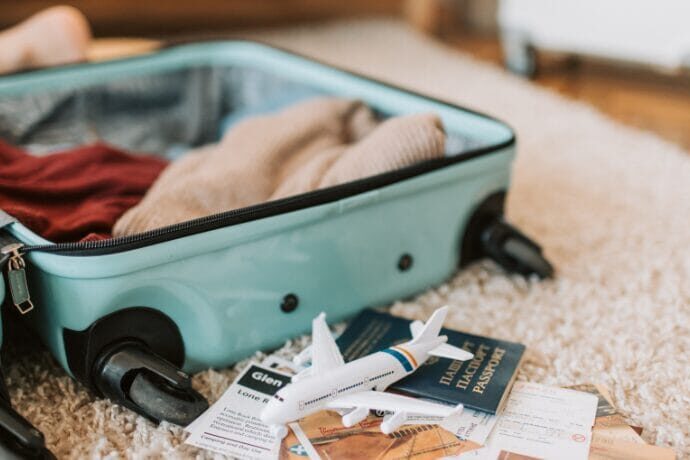 Mala de viagem aberta com roupas organizadas, passaportes e miniatura de avião, representando planejamento de fim de semana no campo com estilo.